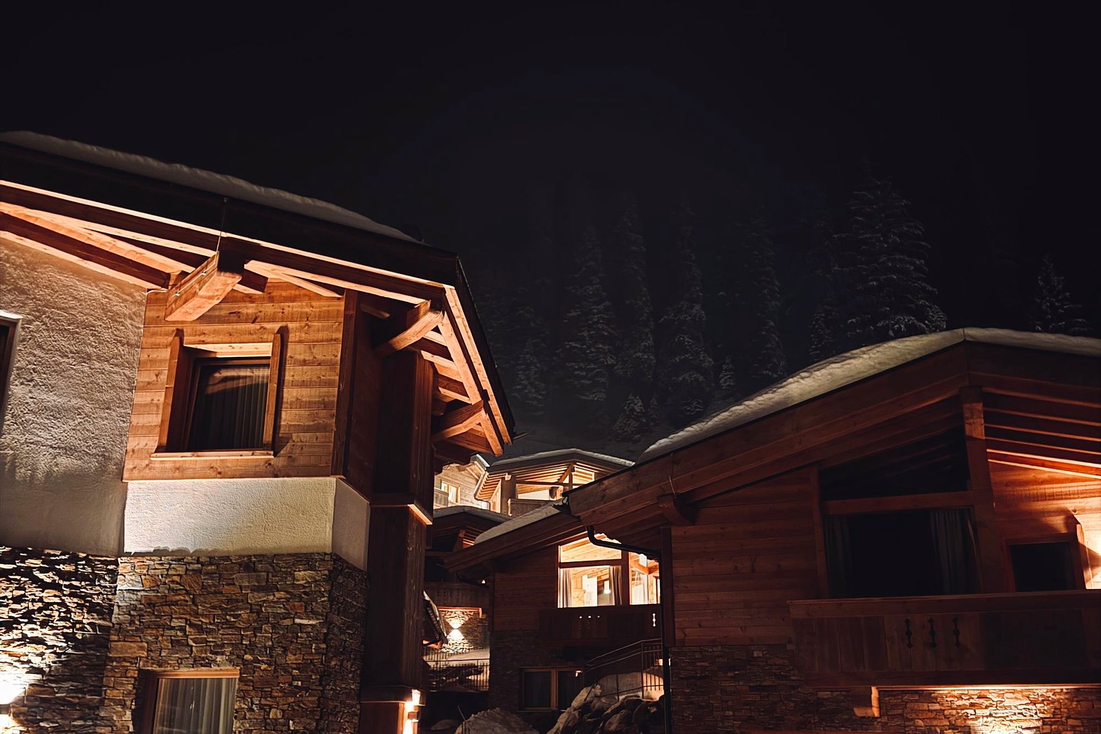 Alpine lodge chalets lit warm against a snowy night.
